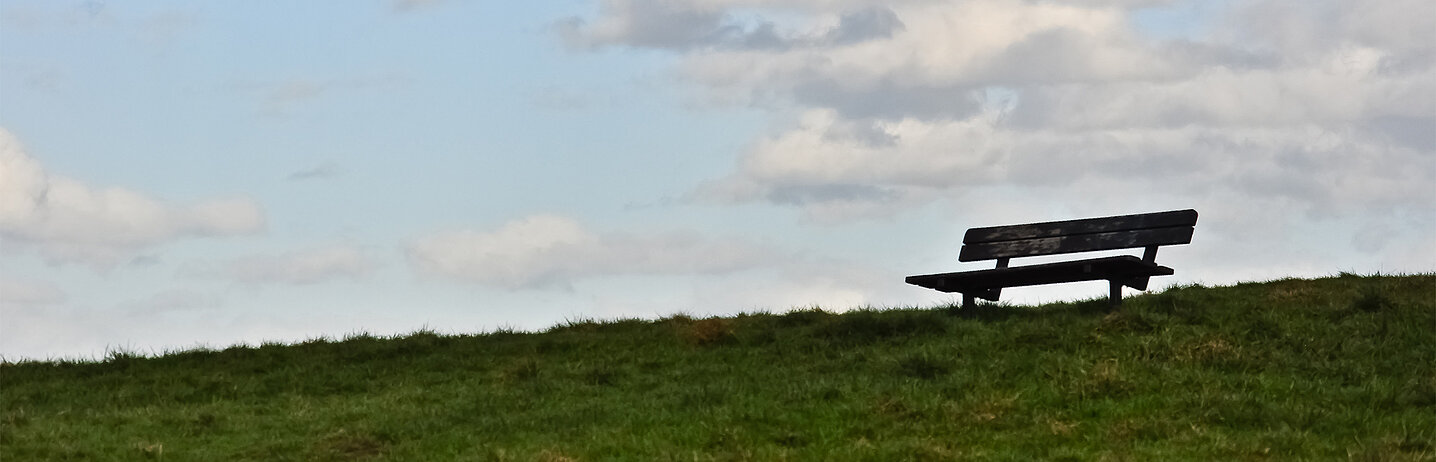 Colline avec un banc, en contre jour, qui se découpe sur l'horizon.