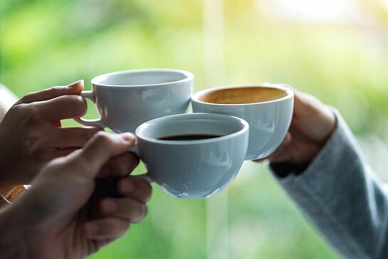 Trois mains portant une tasse et qui trinquent.