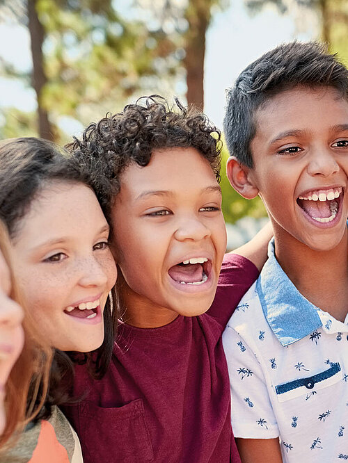 Groupe d'enfants en train de sourire en regardant devant eux avec un air malicieux.