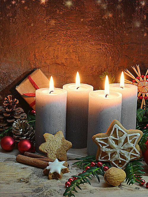 Fourth Advent, four candles are lighted, Christmas decoration and gifts on rustic wooden planks against a dark brown background with copy space, selected focus, narrow depth of field