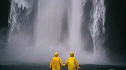 Personnes se tenant la main devant une cascade