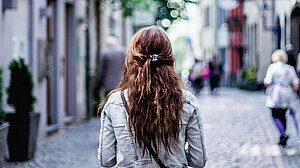 Une femme de dos marche dans la rue