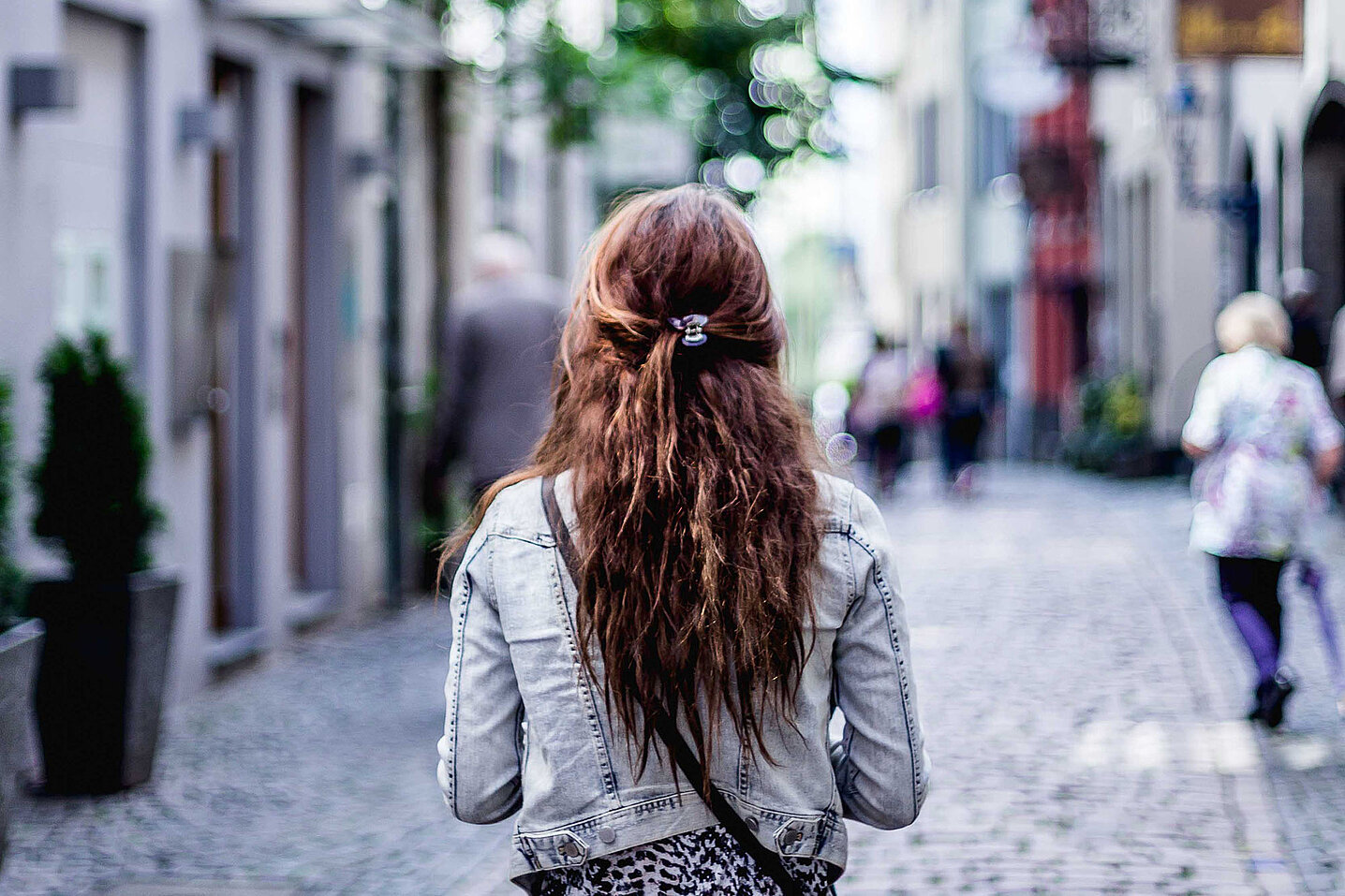 Une femme marche, de dos, dans une rue piétonne en ville.