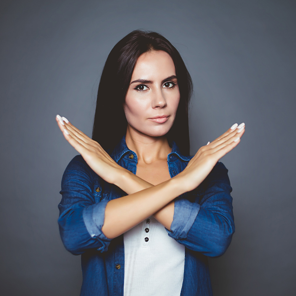 Une femme forme une croix avec ses avant-bras en signe de refus.