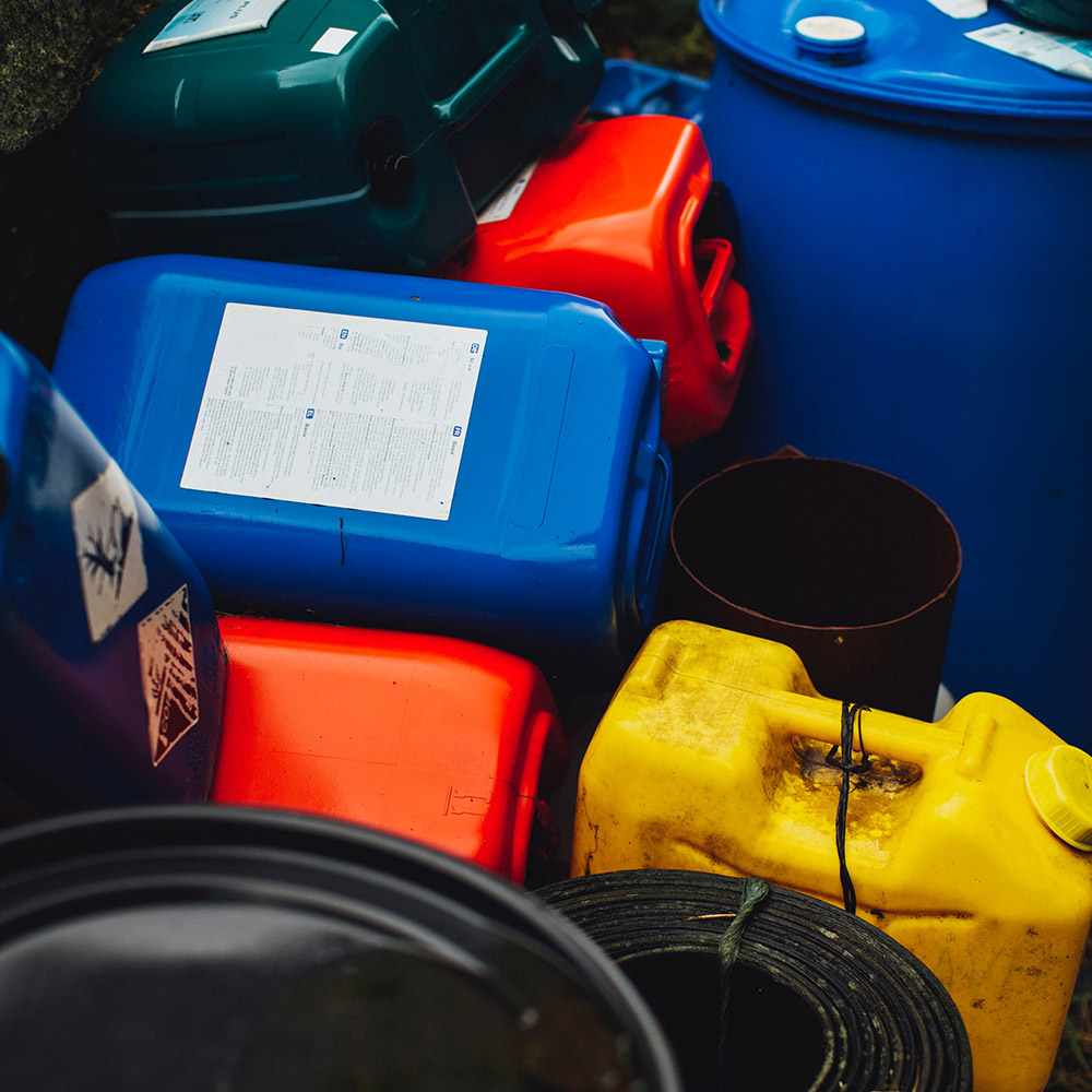 Différents formats de bidons, rouges, jaunes et bleus, entassés de manière désordonnée.